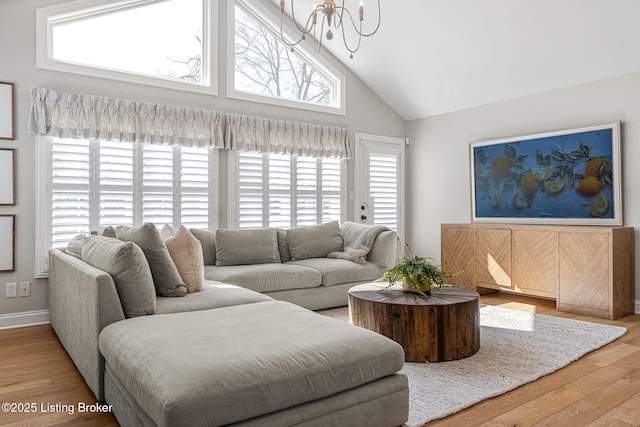 living room featuring an inviting chandelier, wood finished floors, baseboards, and high vaulted ceiling