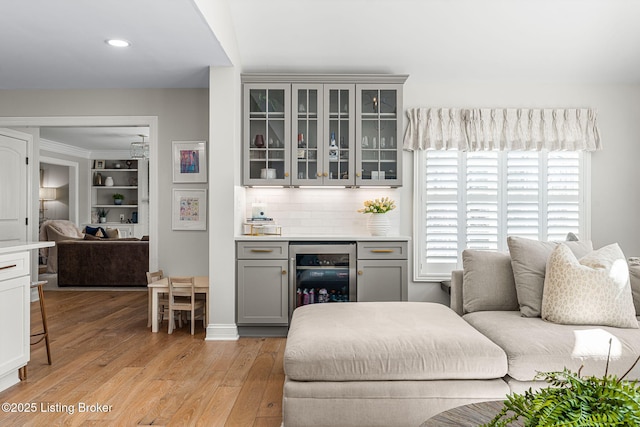 living room with beverage cooler, recessed lighting, a bar, and light wood-type flooring