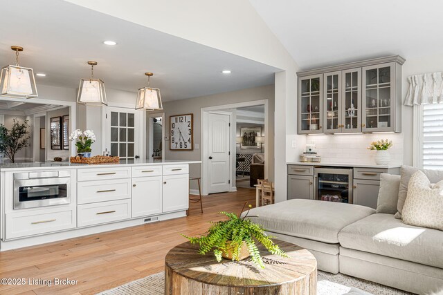 living area featuring wine cooler, recessed lighting, light wood-type flooring, and lofted ceiling