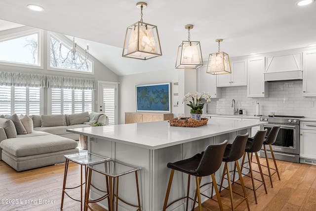 kitchen with light wood-style flooring, a center island, stainless steel electric range, light countertops, and custom exhaust hood