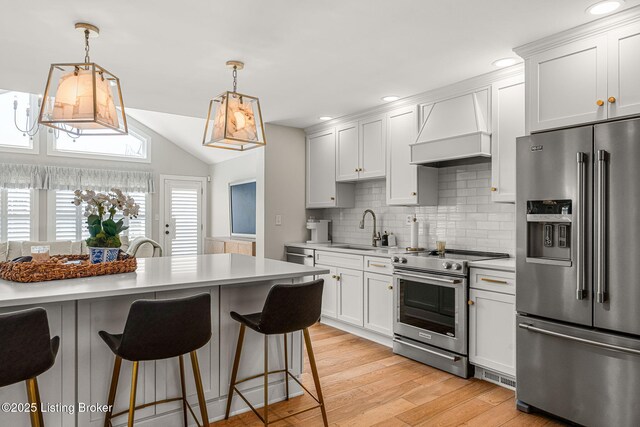 kitchen with premium range hood, a kitchen bar, high quality appliances, a sink, and light countertops