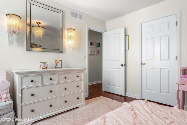 bedroom with visible vents, baseboards, and wood finished floors