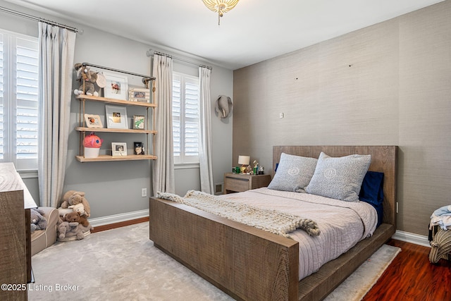 bedroom featuring wallpapered walls, baseboards, and wood finished floors