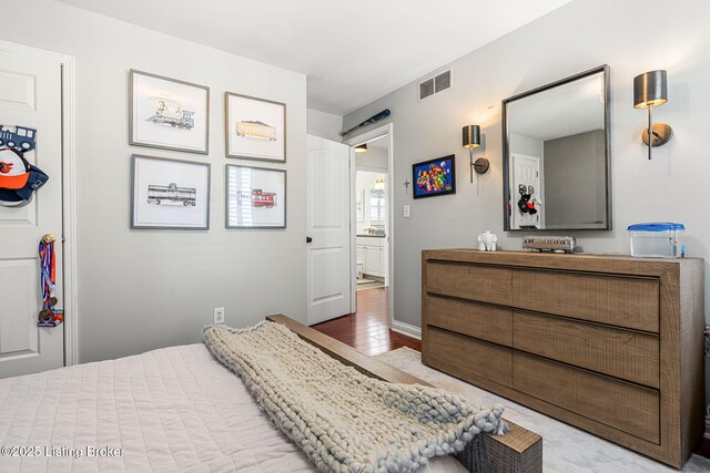 bedroom featuring a barn door, visible vents, and wood finished floors