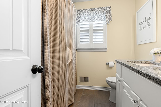 bathroom with visible vents, baseboards, toilet, wood finished floors, and vanity