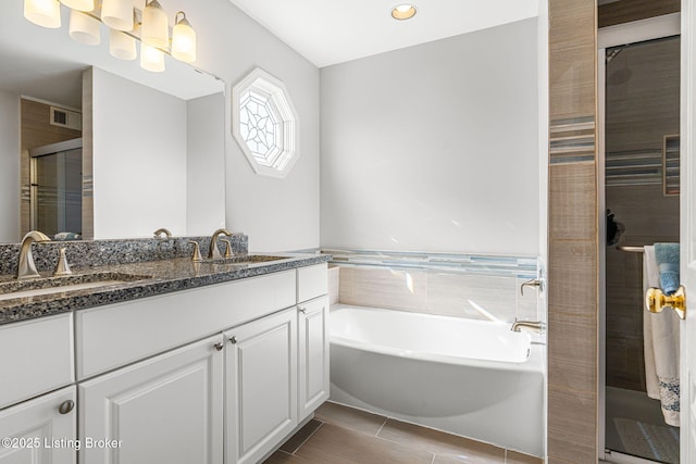 bathroom with a bath, visible vents, a stall shower, and a sink