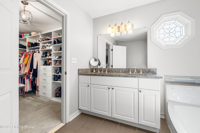 bathroom featuring a walk in closet, vanity, and a bathing tub