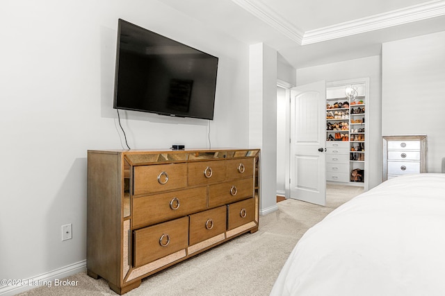 bedroom featuring a walk in closet, crown molding, light colored carpet, and baseboards