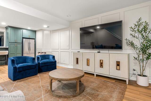 living room featuring a decorative wall, recessed lighting, and light wood-style floors