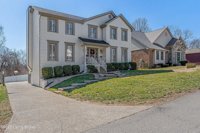 traditional home featuring a front yard, fence, and brick siding