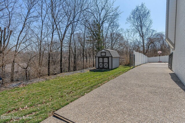 view of yard with driveway, a storage unit, an outdoor structure, and fence