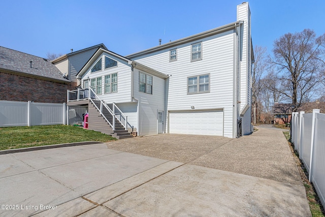 rear view of house with stairway, an attached garage, driveway, and fence