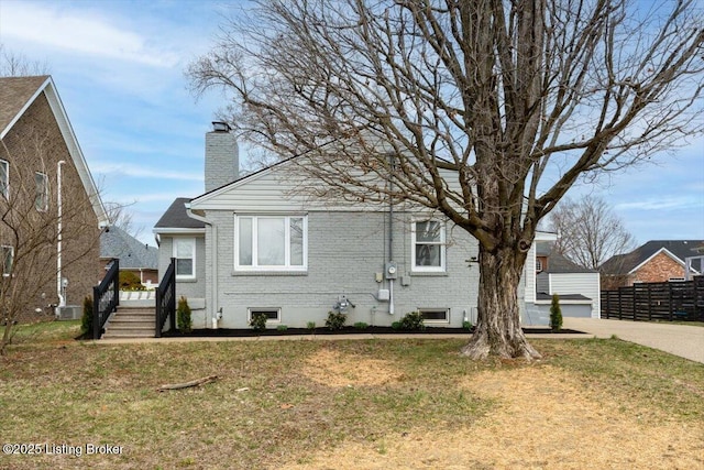 view of front of property with brick siding, a chimney, a front yard, and fence