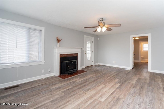 unfurnished living room with ceiling fan, visible vents, baseboards, and wood finished floors