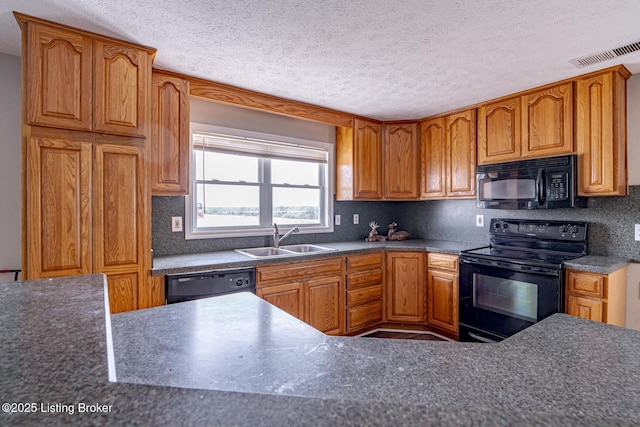 kitchen featuring brown cabinetry, visible vents, black appliances, and a sink