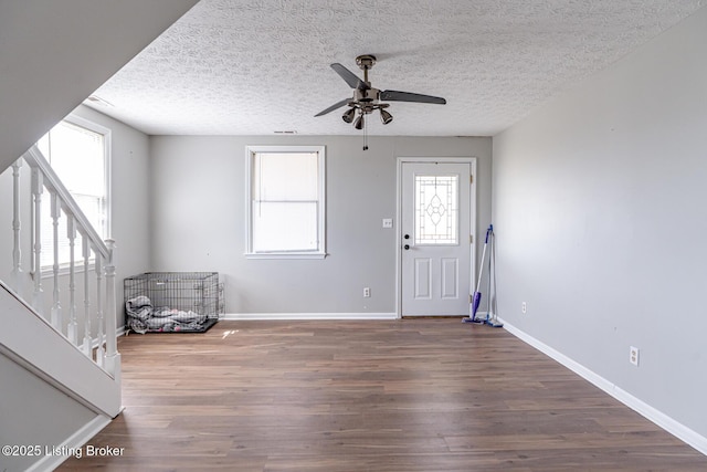 foyer featuring stairway, wood finished floors, a ceiling fan, baseboards, and a textured ceiling