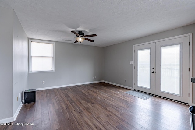 empty room featuring french doors, dark wood-type flooring, ceiling fan, and a textured ceiling