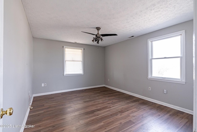 empty room featuring visible vents, baseboards, dark wood-type flooring, and ceiling fan