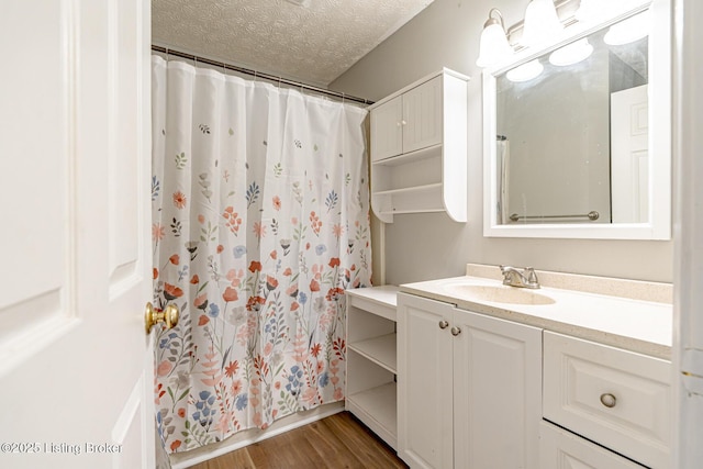 bathroom with a textured ceiling, vanity, a shower with curtain, and wood finished floors