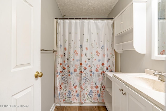 full bath with a textured ceiling, vanity, shower / tub combo, and wood finished floors