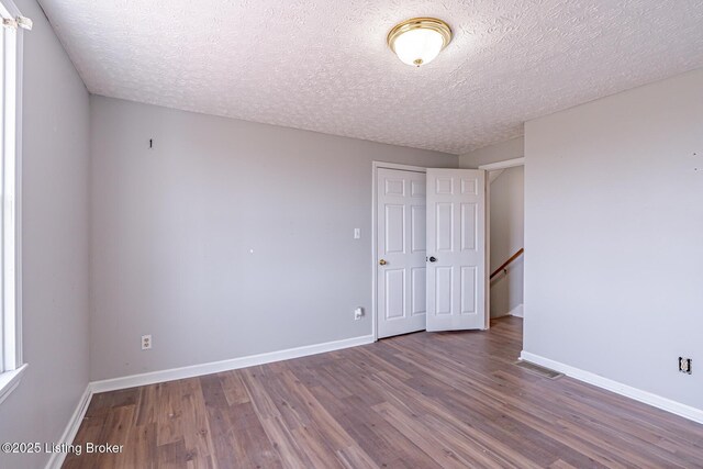 spare room featuring a textured ceiling, baseboards, and wood finished floors