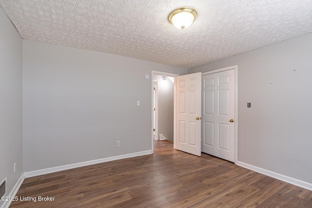 unfurnished bedroom with wood finished floors, baseboards, and a textured ceiling