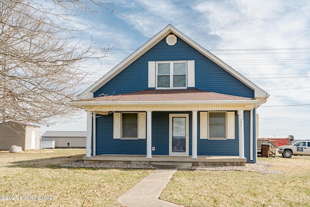 bungalow-style home featuring covered porch, a shingled roof, and a front lawn