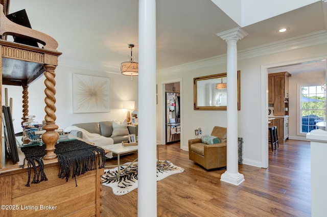 living room featuring baseboards, wood finished floors, ornamental molding, and ornate columns