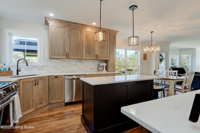 kitchen with a sink, backsplash, appliances with stainless steel finishes, crown molding, and light countertops