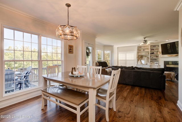 dining area with a fireplace, dark wood-style floors, and ornamental molding