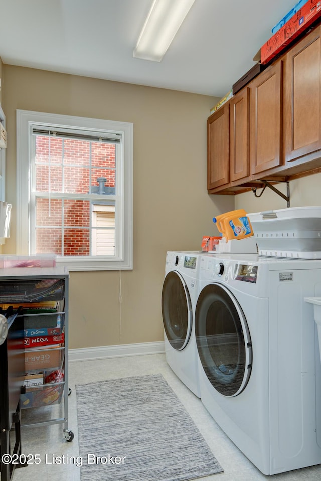 washroom with cabinet space, washer and dryer, and baseboards