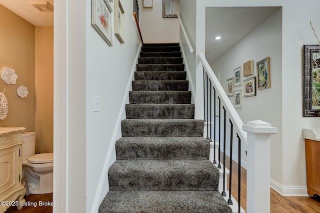 staircase featuring visible vents, recessed lighting, baseboards, and wood finished floors