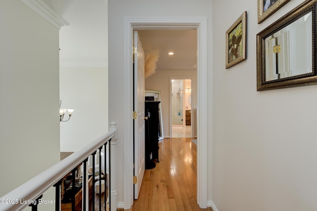 hallway with baseboards, a notable chandelier, ornamental molding, and light wood finished floors