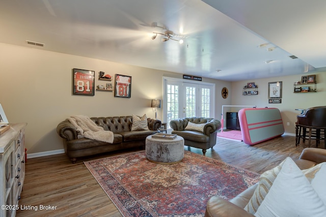 living room featuring visible vents, french doors, baseboards, and wood finished floors