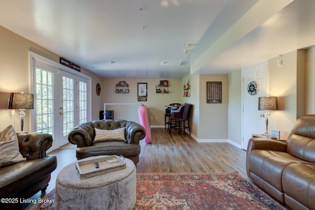 living room with french doors, baseboards, and light wood finished floors