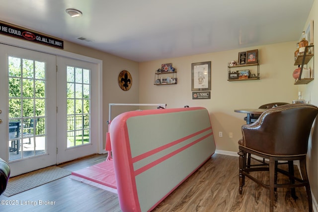 bedroom featuring access to exterior, visible vents, baseboards, and wood finished floors