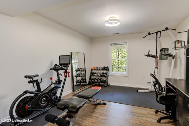 workout room featuring visible vents, wood finished floors, and baseboards