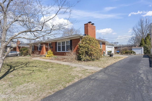 ranch-style house with a garage, a front yard, brick siding, and a chimney