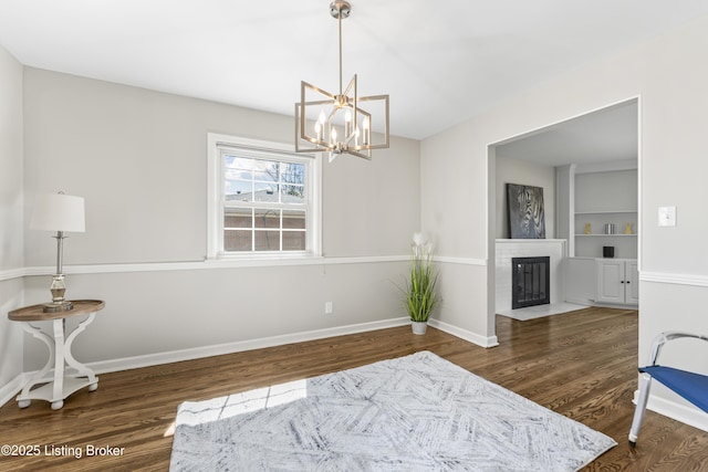 sitting room with built in features, baseboards, wood finished floors, and a fireplace