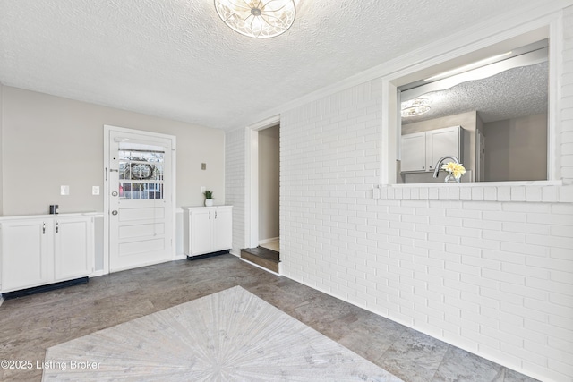 interior space with a textured ceiling and brick wall