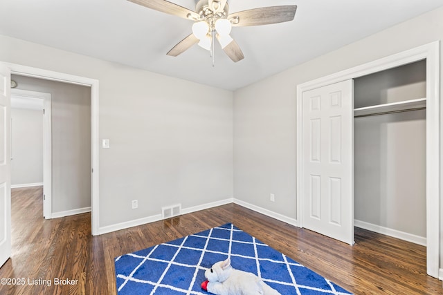 unfurnished bedroom with a closet, visible vents, baseboards, and wood finished floors