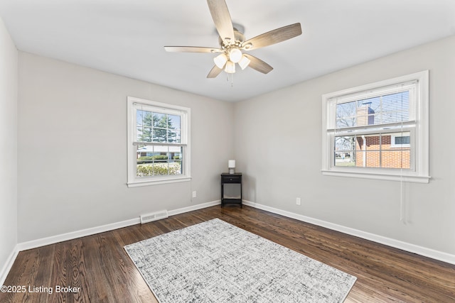 unfurnished room with visible vents, ceiling fan, baseboards, and dark wood-style flooring