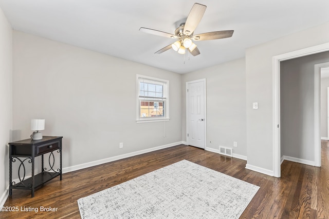 interior space featuring a ceiling fan, dark wood-type flooring, baseboards, and visible vents