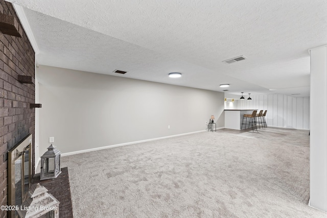 unfurnished living room featuring visible vents, a bar, a brick fireplace, and carpet