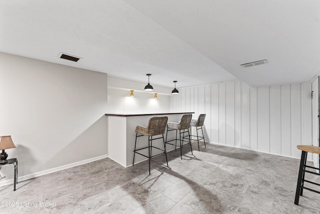 bar featuring decorative light fixtures, visible vents, and baseboards