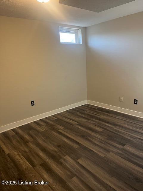 spare room with dark wood-type flooring and baseboards