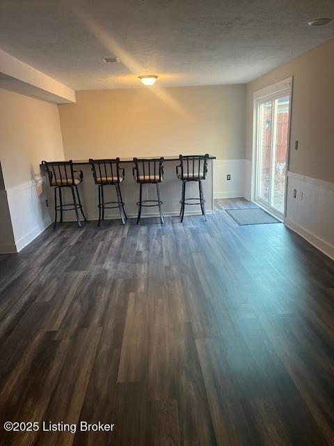 interior space with dark wood-style floors, visible vents, and wainscoting