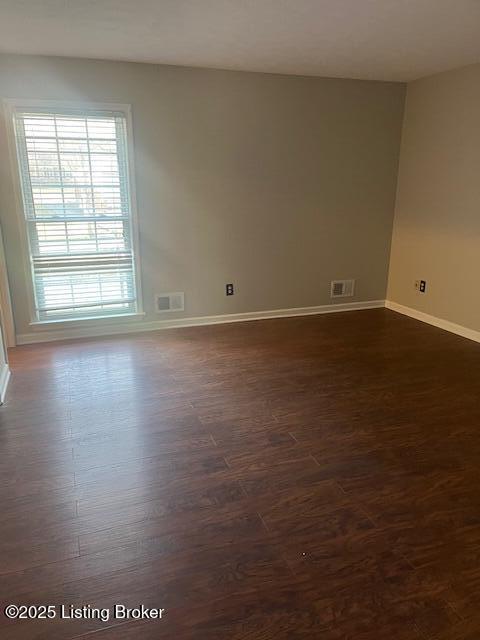 spare room with visible vents, baseboards, and dark wood-style flooring