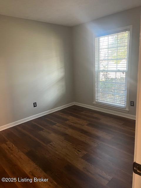 spare room featuring baseboards and dark wood-style flooring