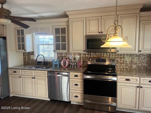 kitchen with cream cabinetry, stainless steel appliances, a ceiling fan, and a sink